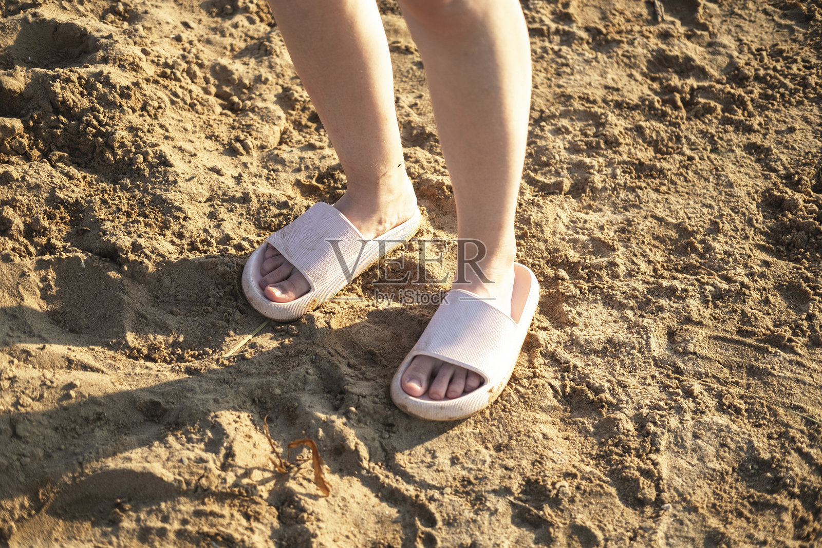 一个穿着人字拖的男人的脚踩在沙滩上。夏季假期的概念,海边的悠闲时光。照片摄影图片