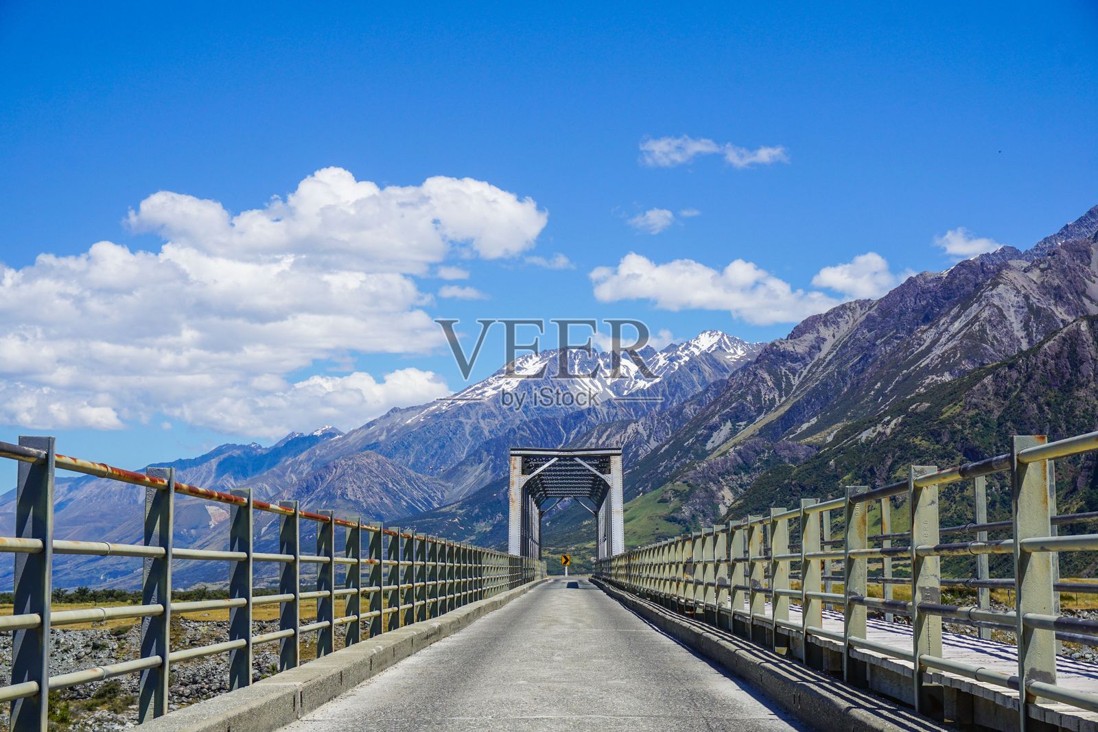 一座桥通向雪山,蓝天明亮。照片摄影图片