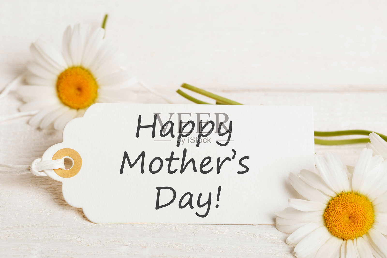 母亲节的白色构图,包含白色雏菊和写有“母亲节快乐”温馨文字的卡片,主题由柔和的光线突出,强调通过文字和白色优雅传达的爱。照片摄影图片