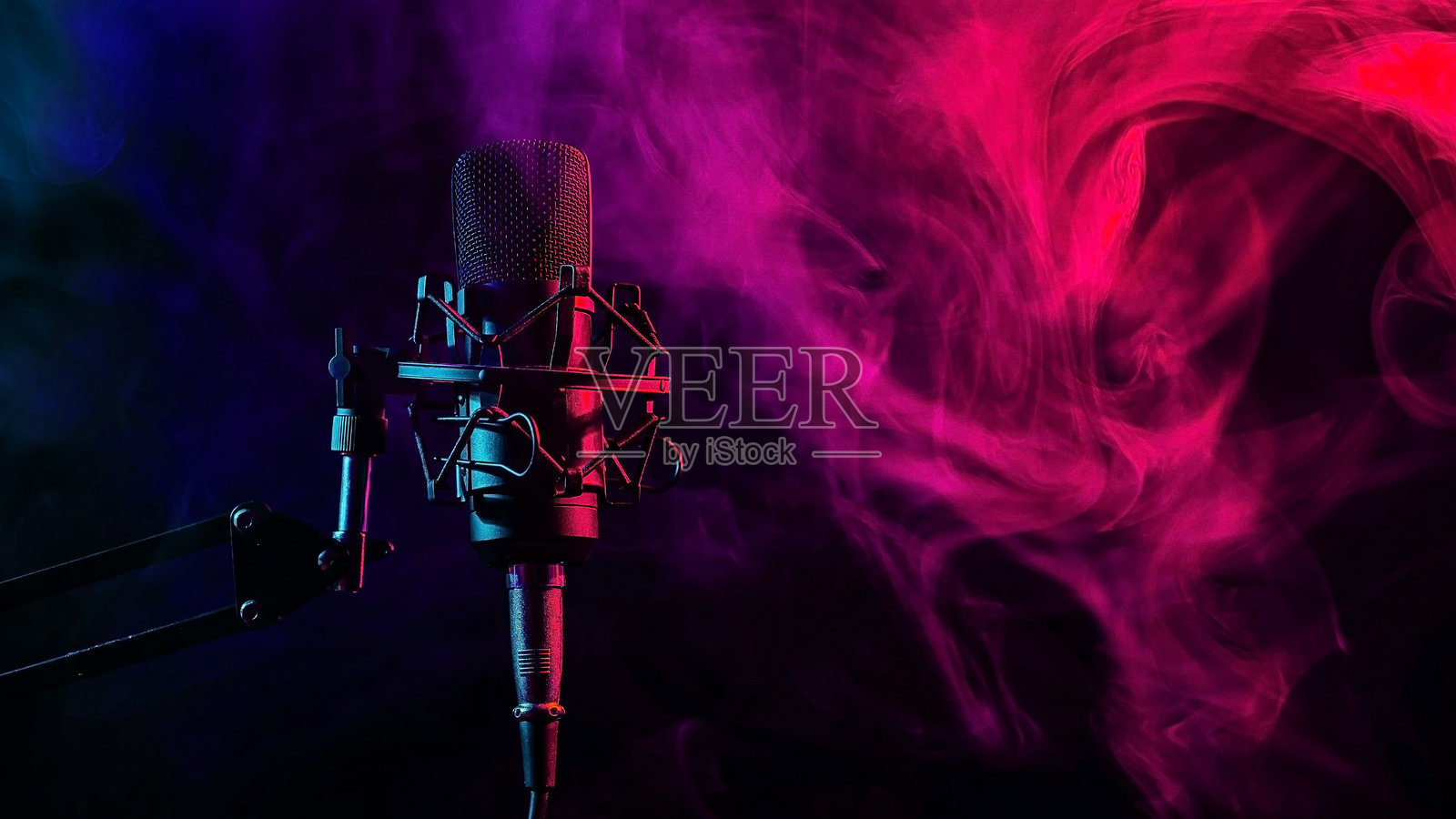 黑色背景上的红蓝烟雾中的专业麦克风。照片摄影图片