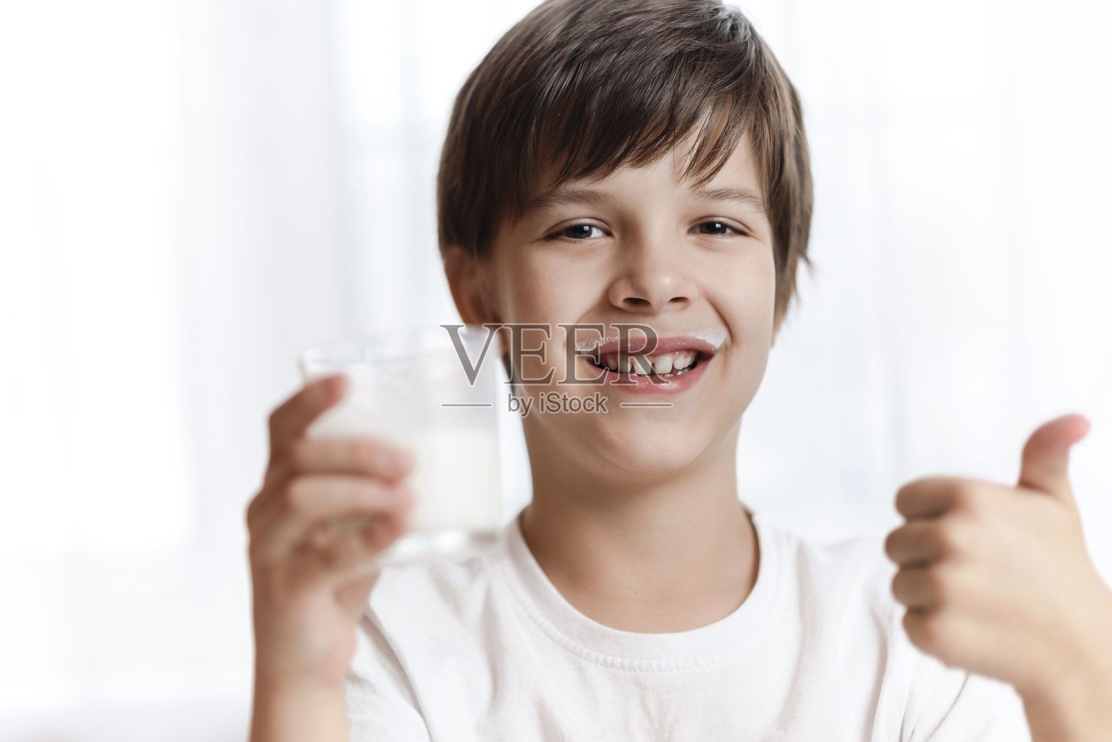 可爱的小孩在白色背景下微笑着拿着一杯牛奶照片摄影图片