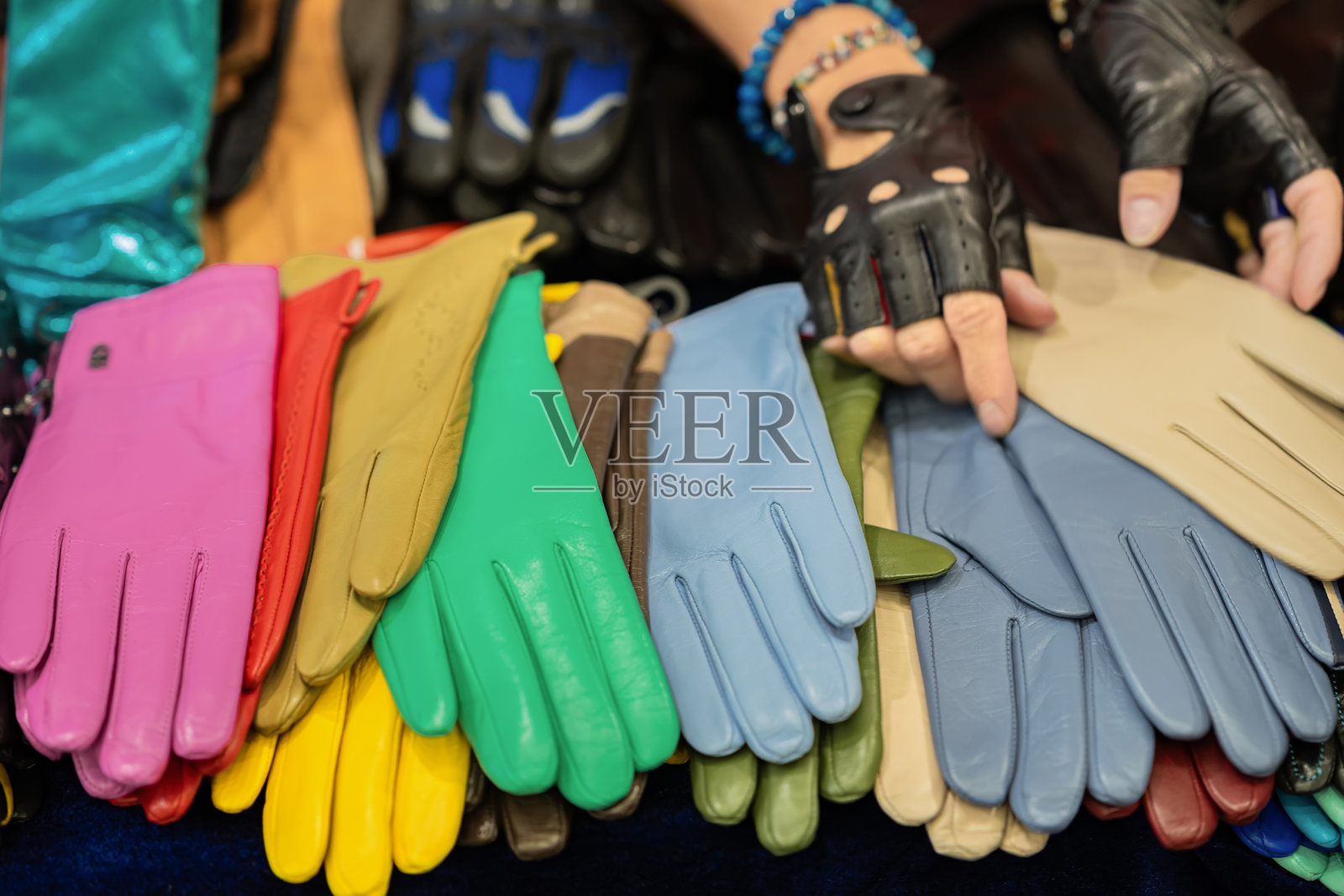 柜台上摆放着各种颜色鲜艳的女性手套,卖家的手在旁边。照片摄影图片