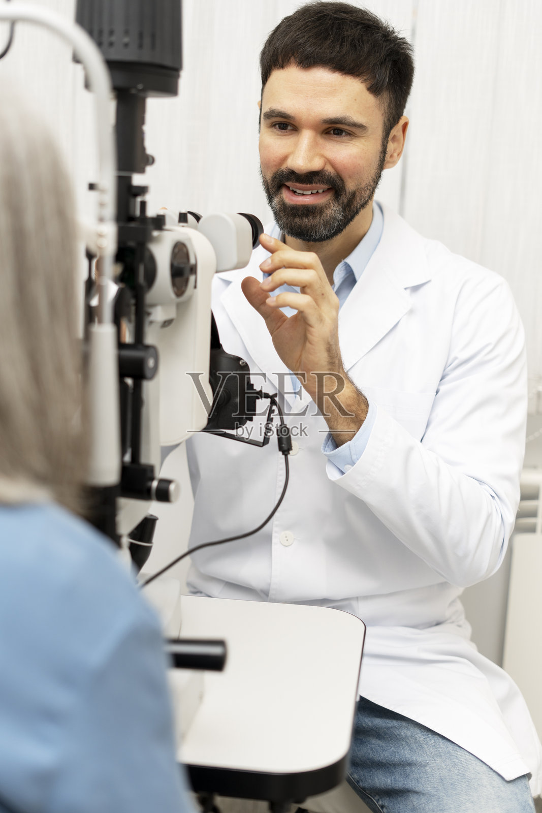 眼科医生使用裂隙灯为患者进行眼部检查照片摄影图片