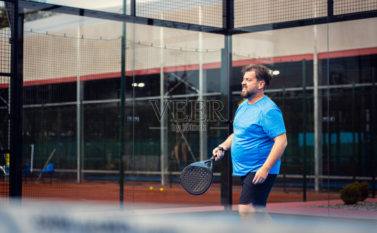中年男子在户外场地打壁球。照片摄影图片