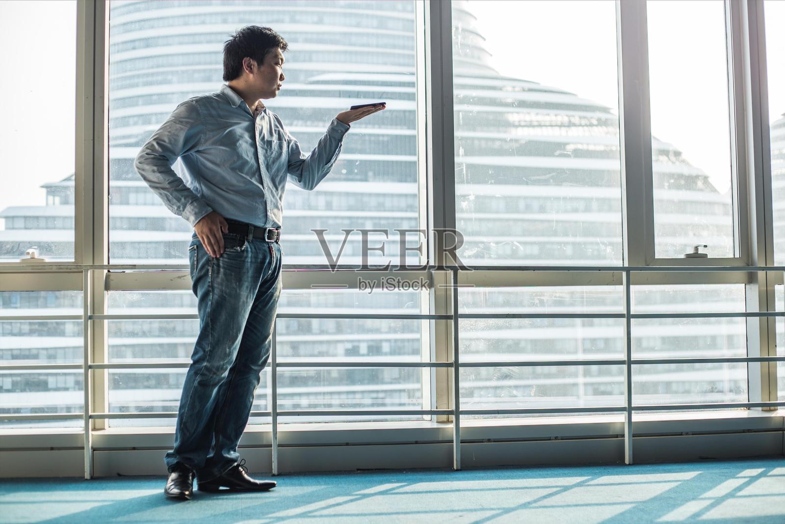 亚洲商人从办公室窗户俯瞰城市景观照片摄影图片