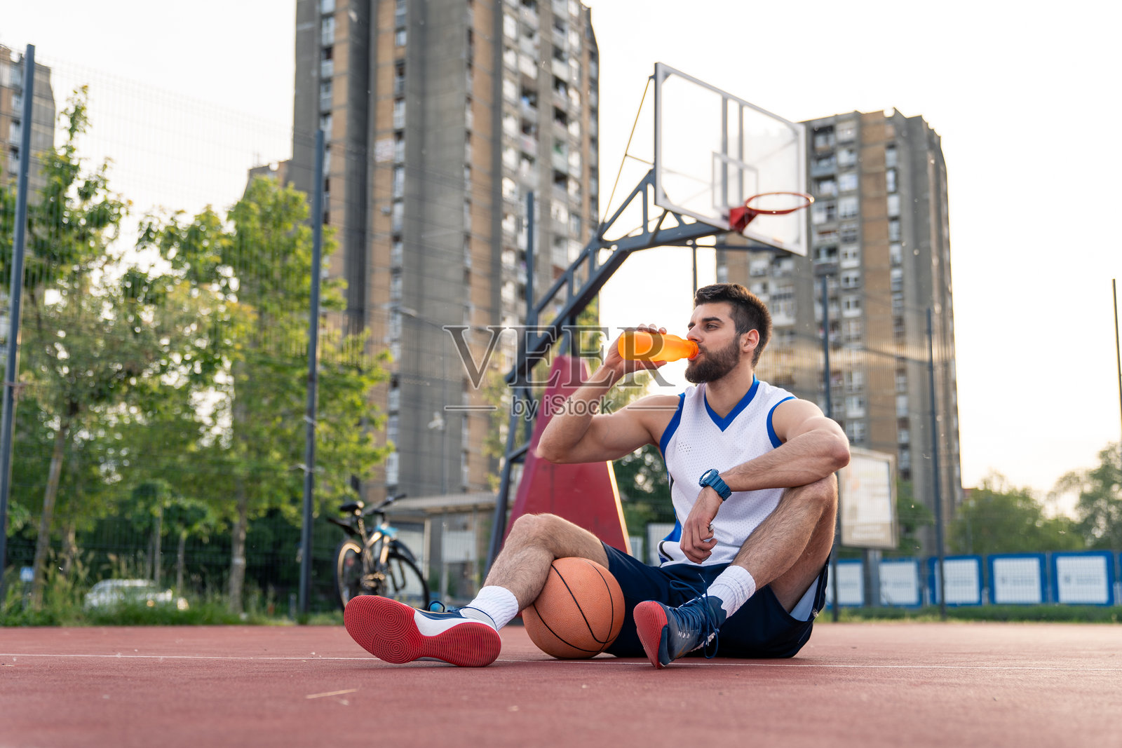 年轻男性运动员在篮球比赛后休息并喝水照片摄影图片