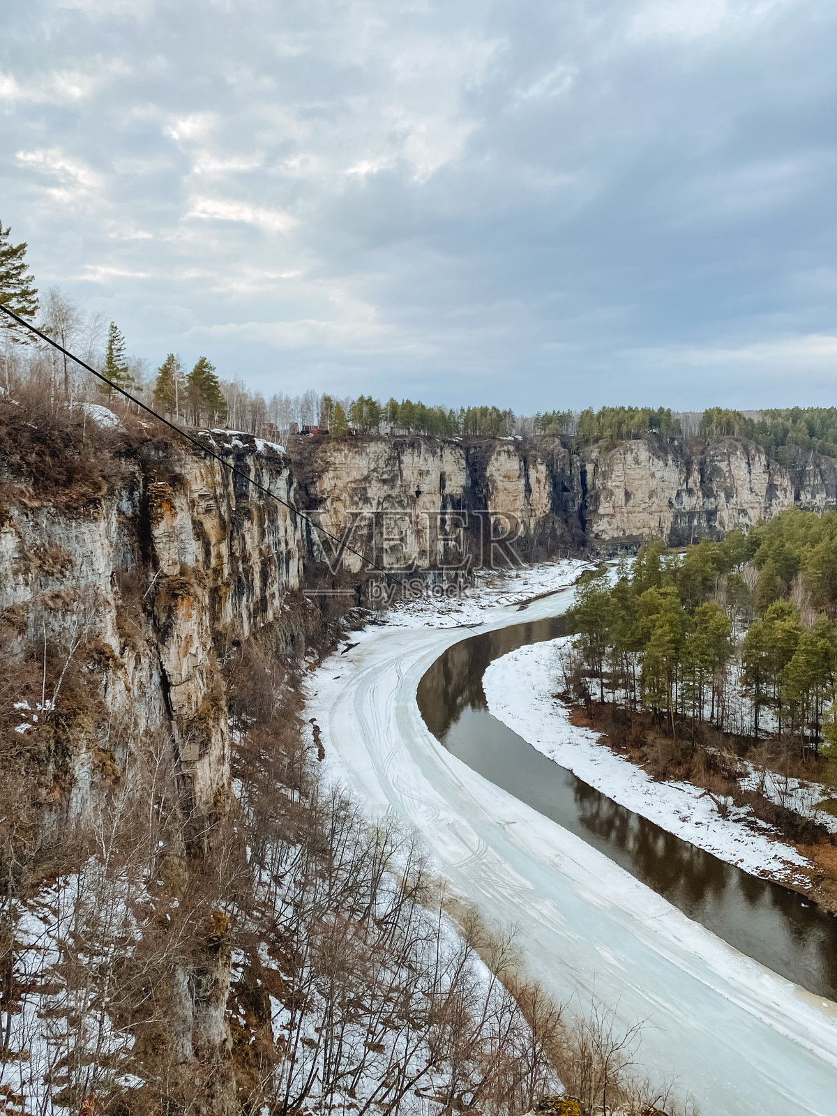 一条美丽的河流优雅地穿过如画的雪景,背景中巍峨的悬崖增添了自然艺术作品的宁静与壮丽。照片摄影图片