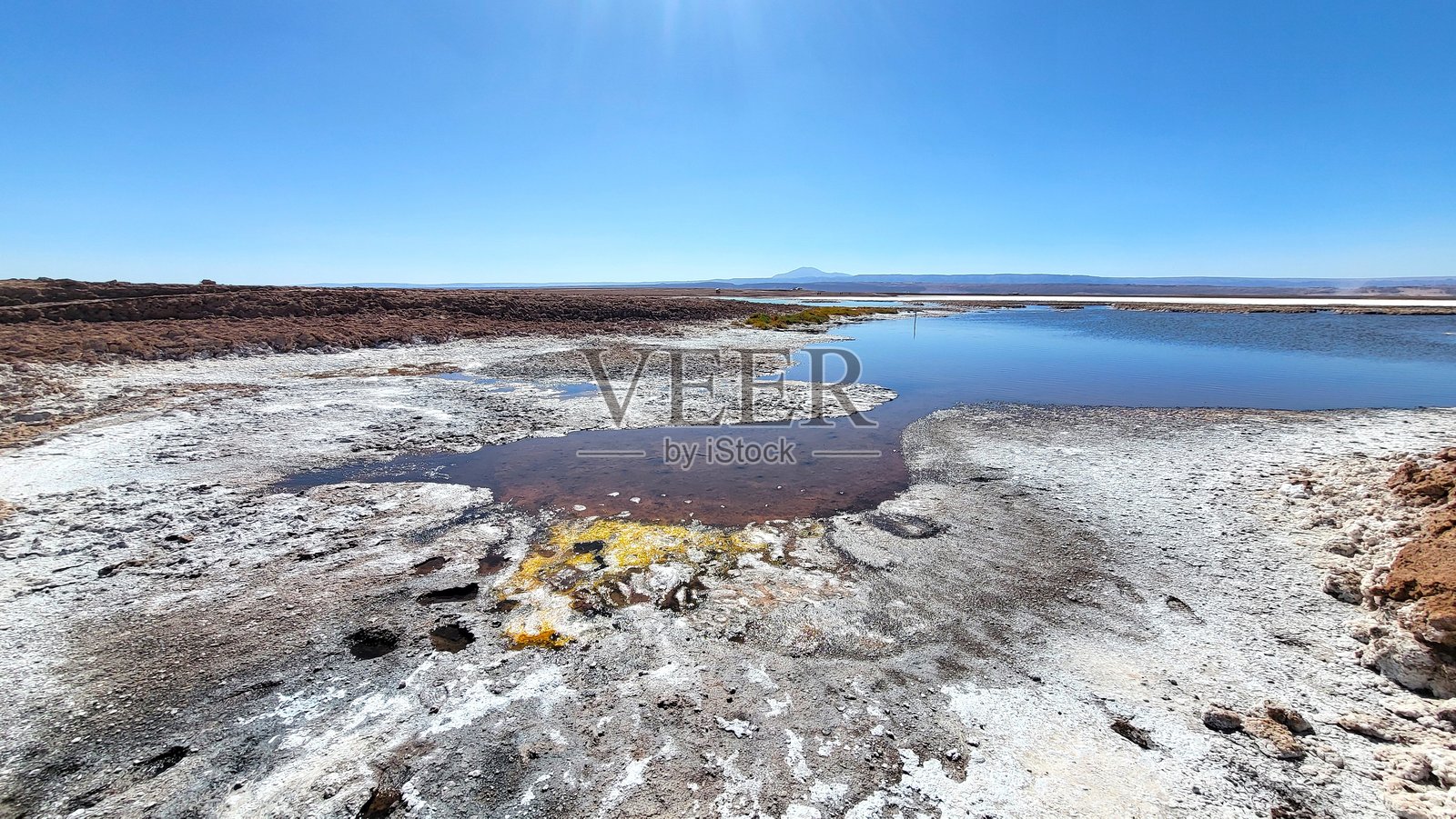 阿塔卡马盐滩的景观,前景是盐滩,背景是安第斯山脉和湛蓝的天空。照片摄影图片