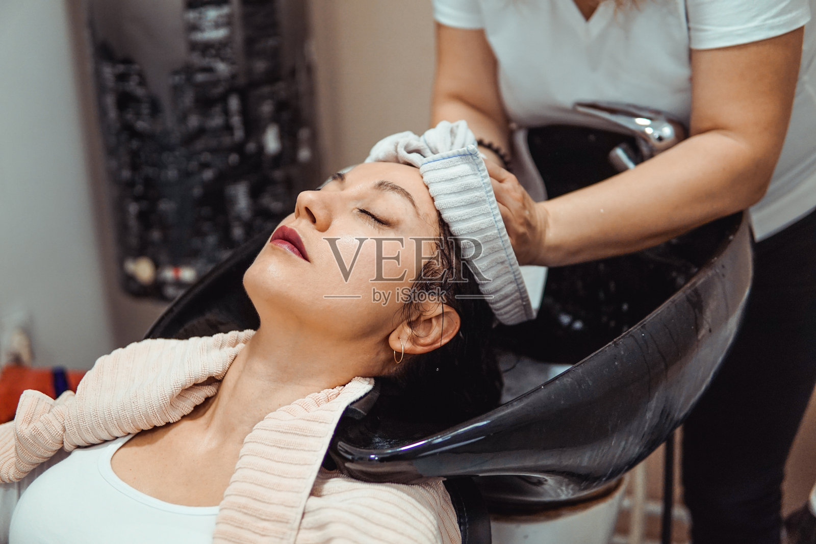 女性在美容院由美发师洗头。照片摄影图片