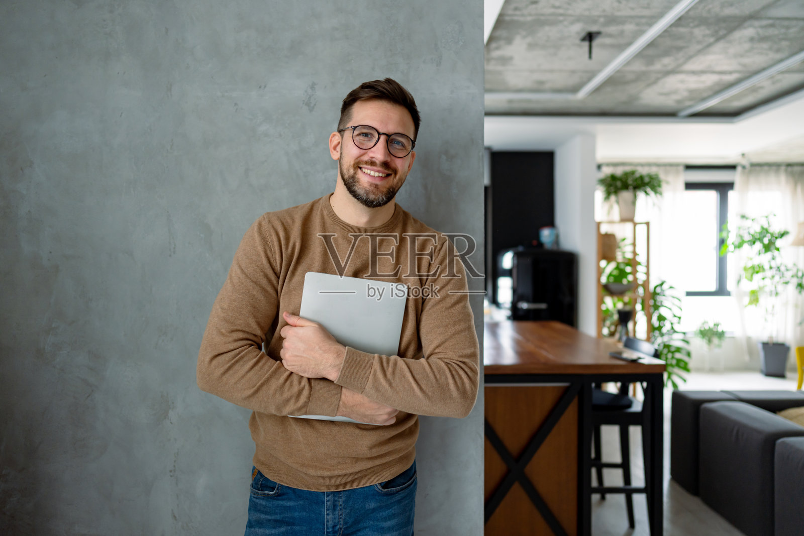 年轻男子微笑着在现代公寓中拿着笔记本电脑照片摄影图片