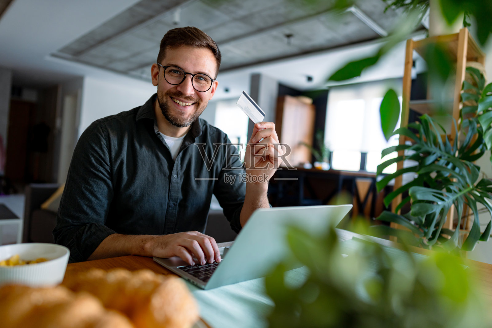 年轻男子在家用信用卡和笔记本电脑进行在线购物照片摄影图片