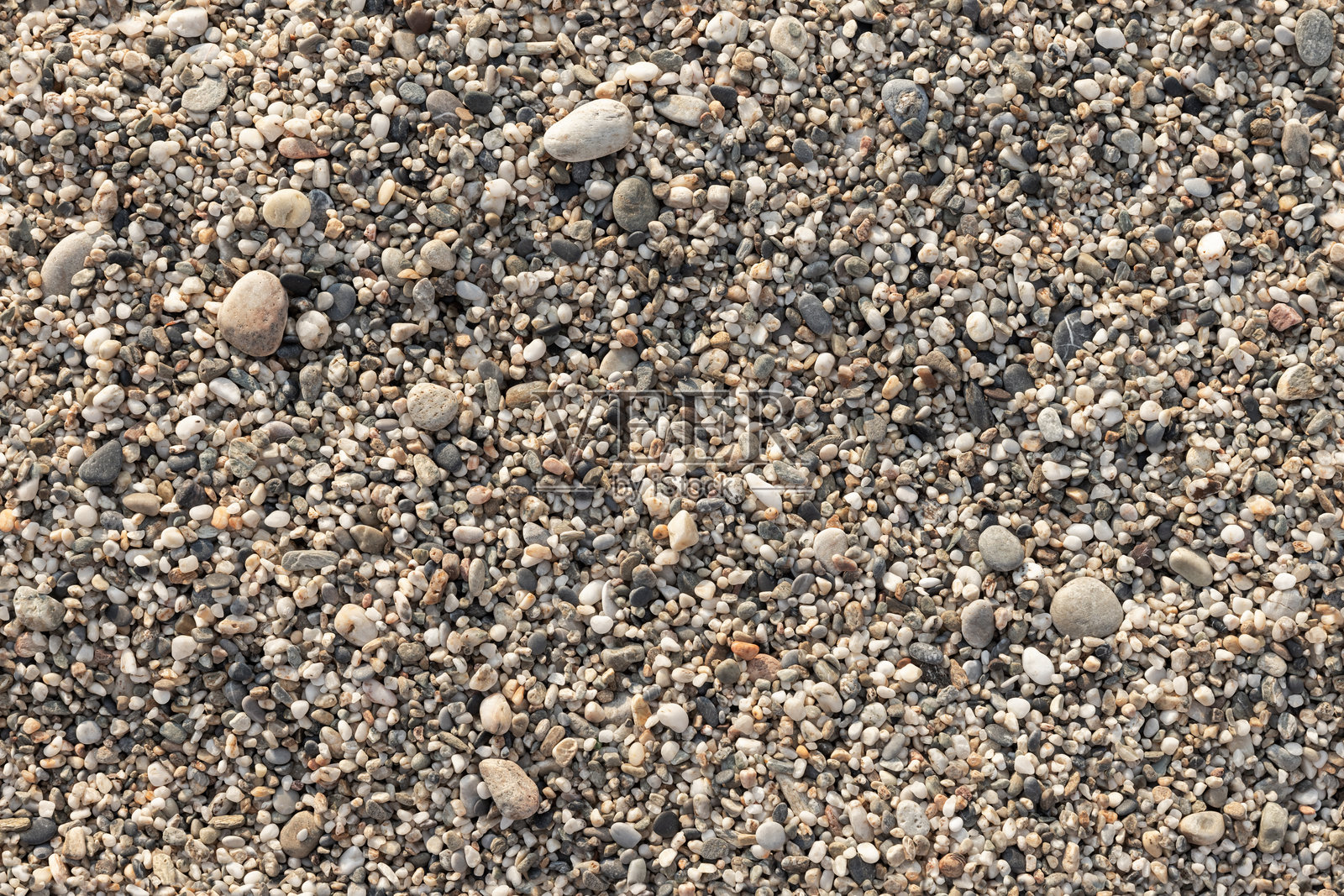 阳光下的海岸卵石与粗沙混合,俯视图照片摄影图片
