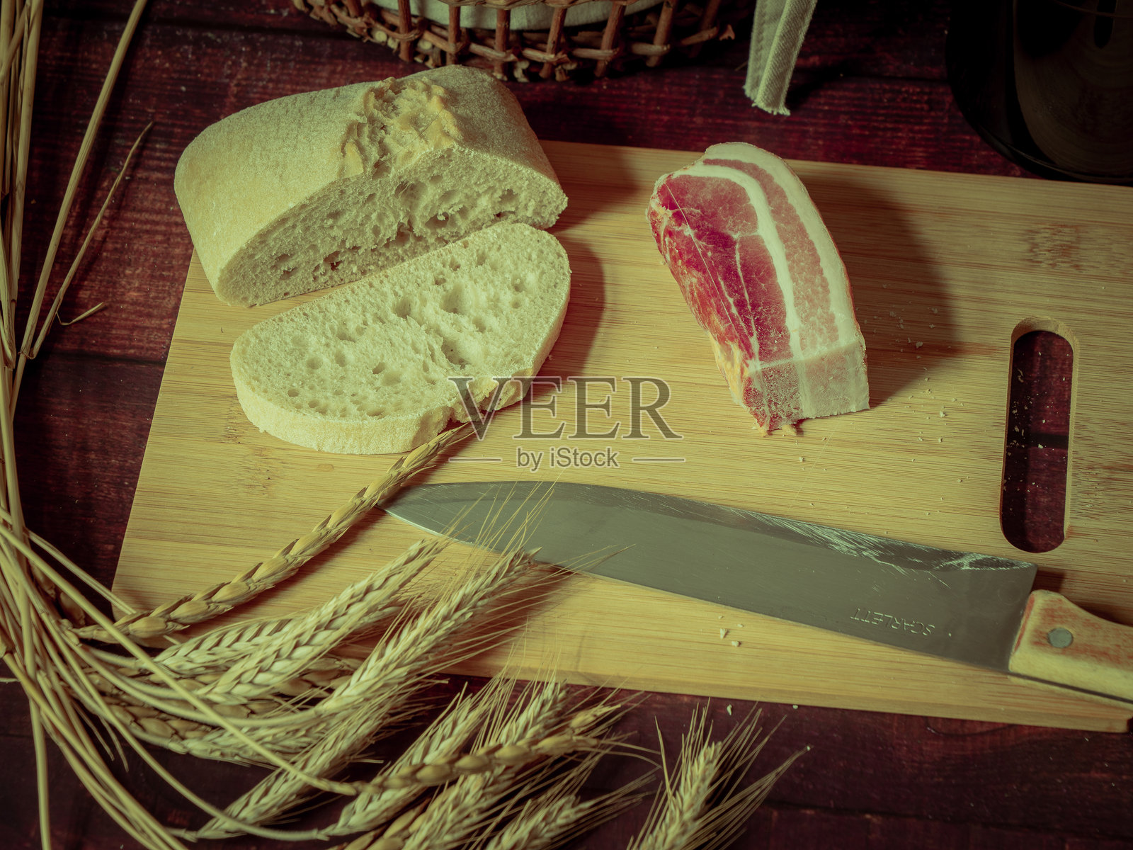 古风质朴的静物画配上面包、麦穗、火腿和培根。照片摄影图片