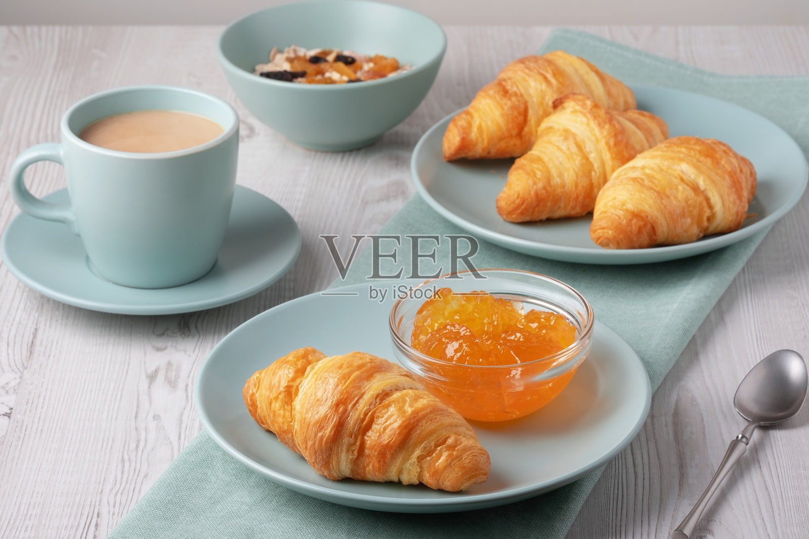 新鲜出炉的可颂面包配果酱和咖啡,摆放在浅色木桌上照片摄影图片