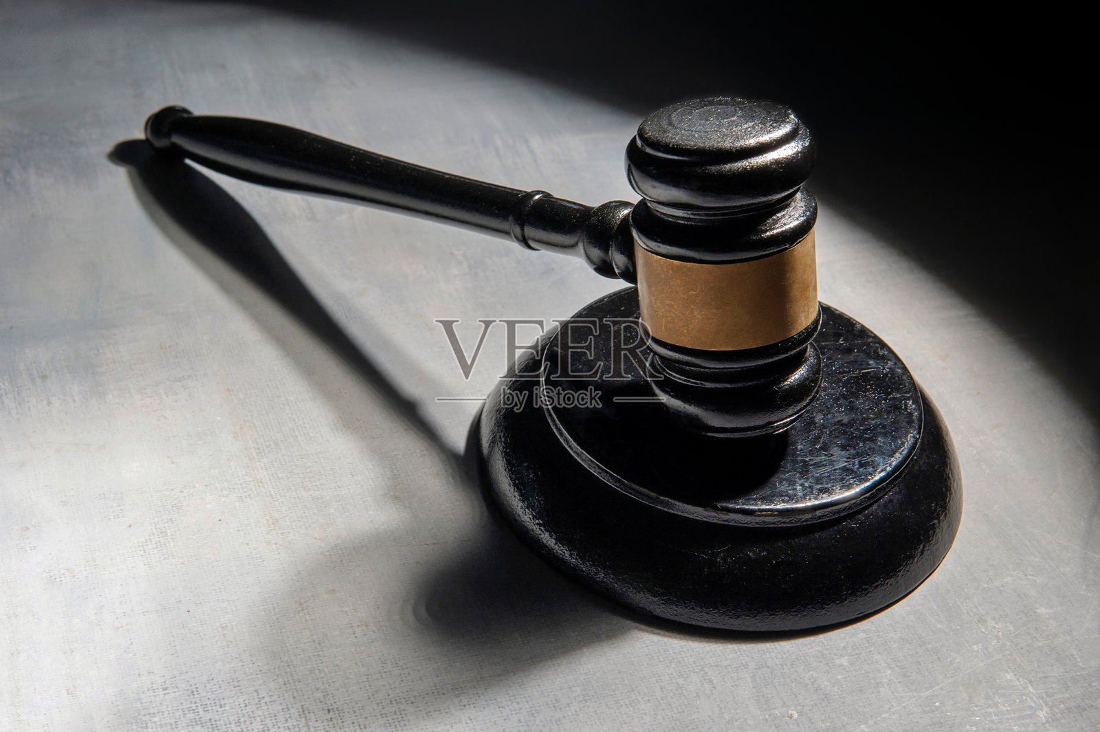 一个在单一光源照射下的表面上的法槌,投射出戏剧性的阴影。照片摄影图片