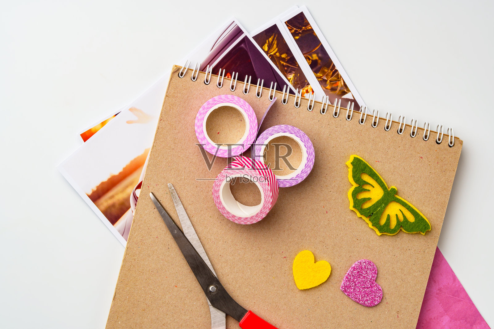 桌子上摆放着工艺用品,包括彩色胶带、剪刀和装饰纸剪贴,准备进行创意项目。照片摄影图片