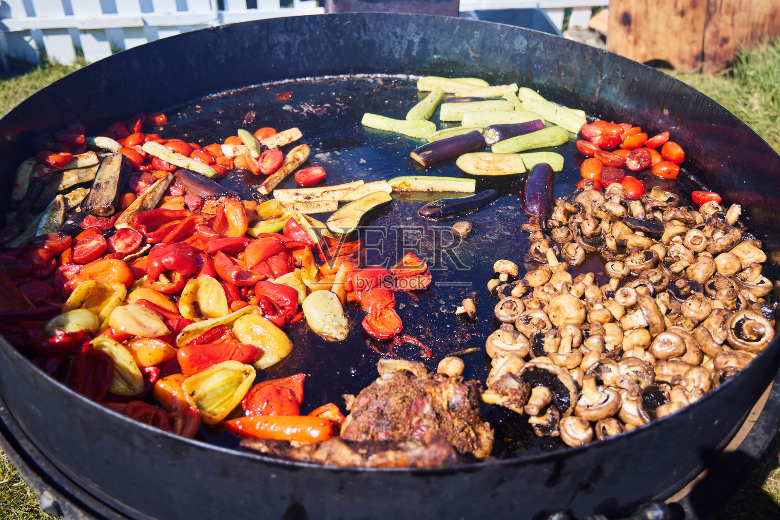 各种蔬菜在一个巨大的锅中用油烹饪。照片摄影图片