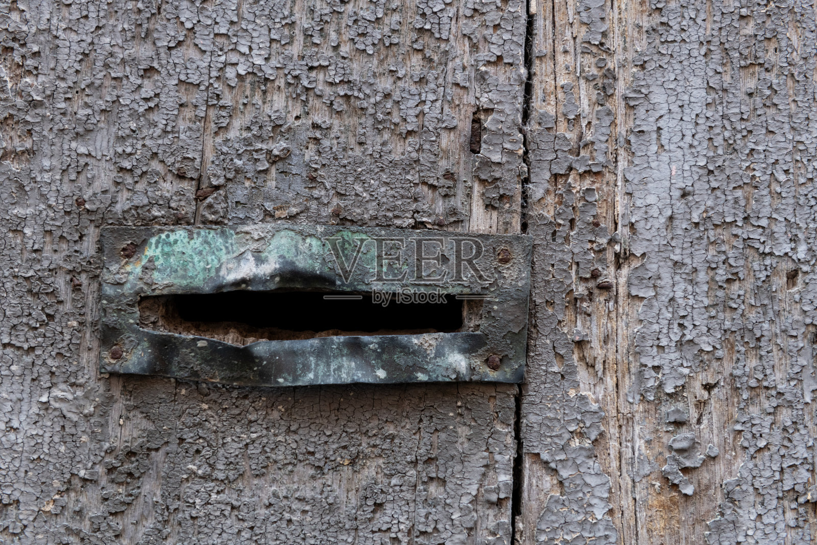 一扇饱经风霜的旧门上弯曲的邮筒照片摄影图片
