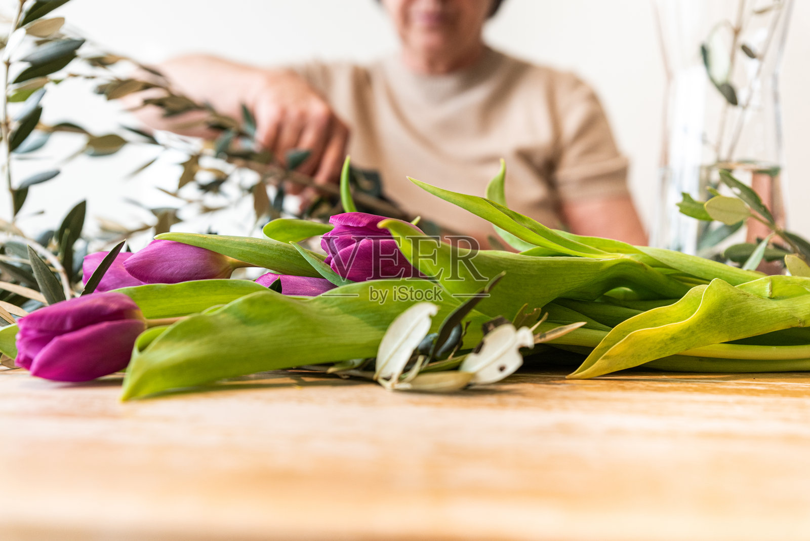 在家中为紫色郁金香和橄榄枝插花的老年女性照片摄影图片