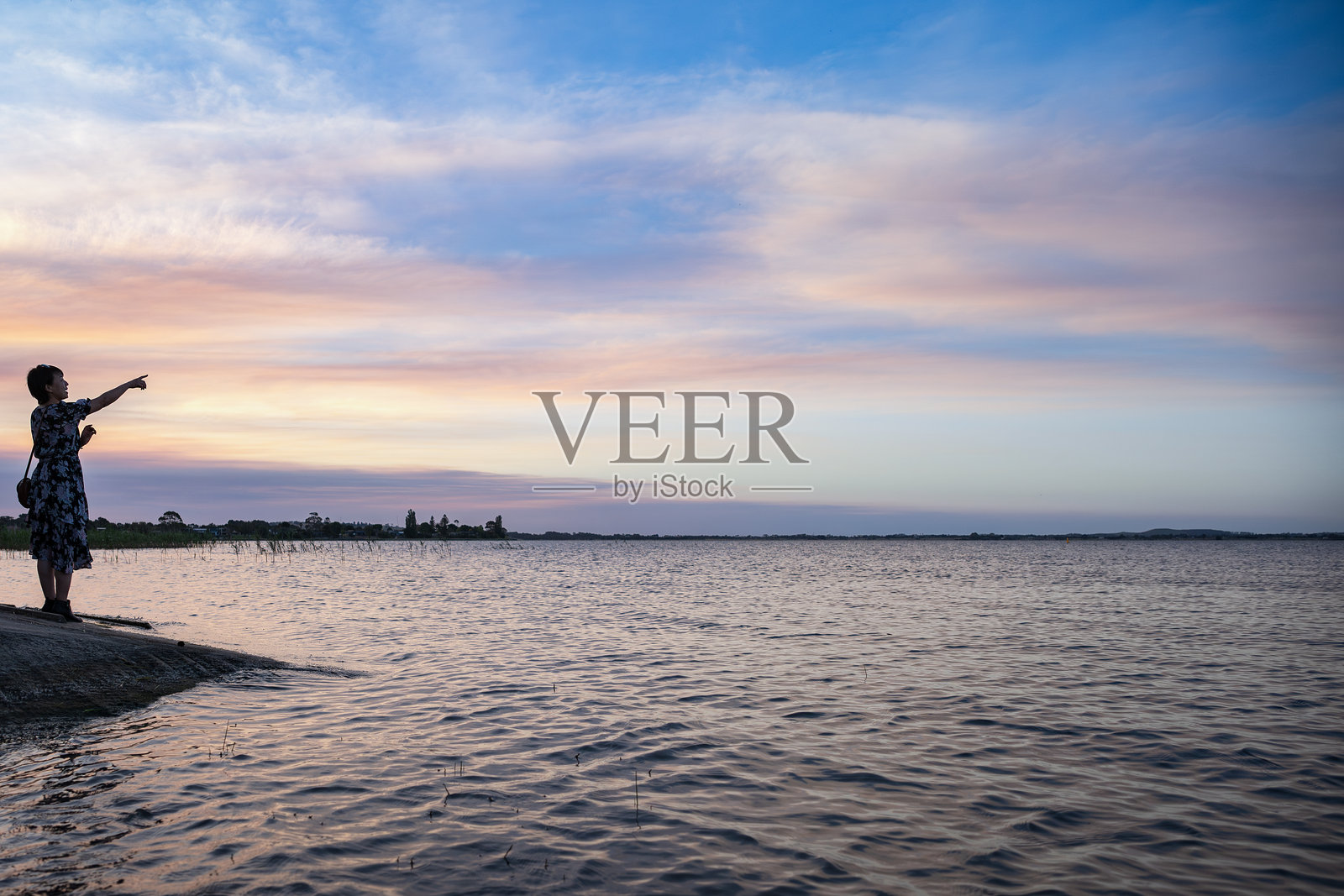 一位女性站在湖边,欣赏着澳大利亚维多利亚州科拉克湖黄昏时分的美丽景色。照片摄影图片