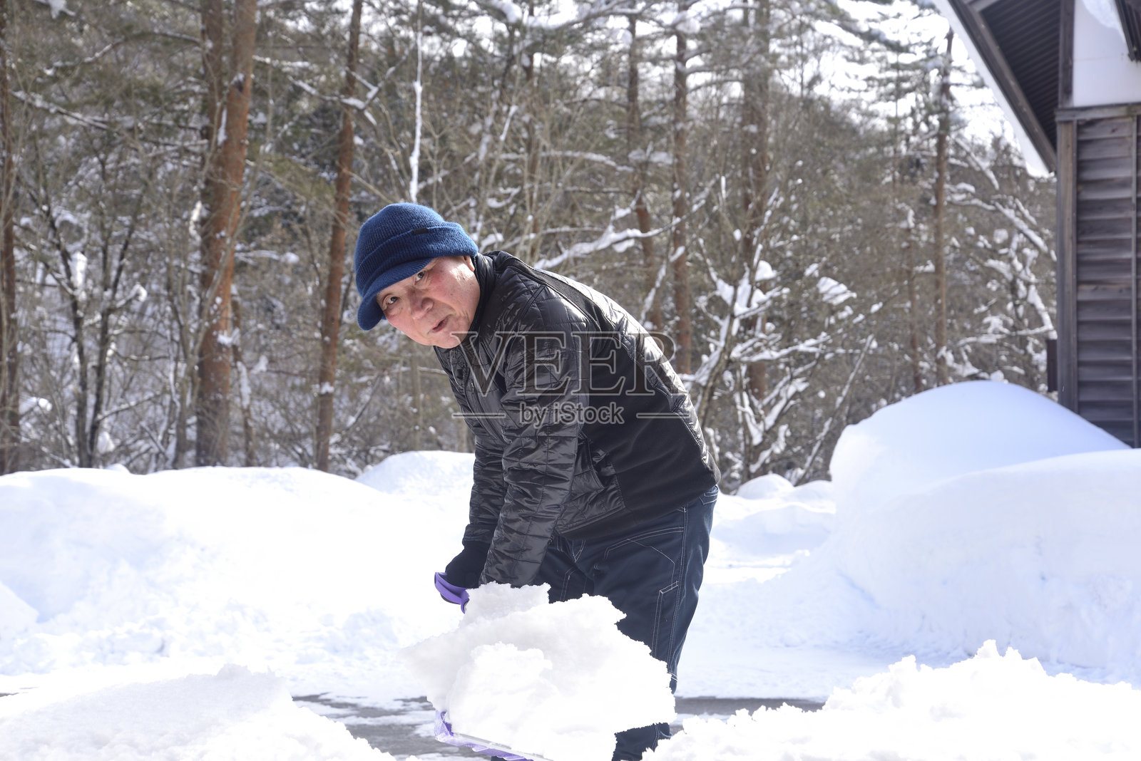 一位微笑的老人正在用雪犁清除雪地中的积雪照片摄影图片