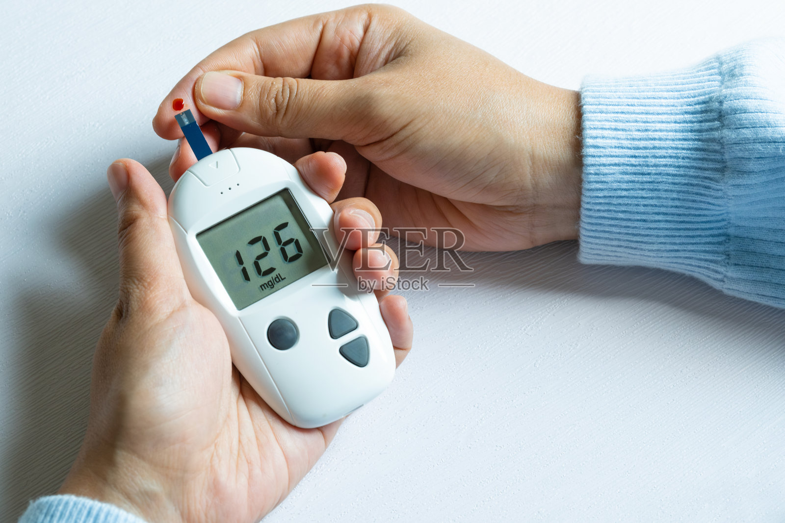 一名女性在他的手指上抽血并测试糖尿病。使用数字血糖测试仪检查高血糖水平。健康护理和医疗概念照片摄影图片