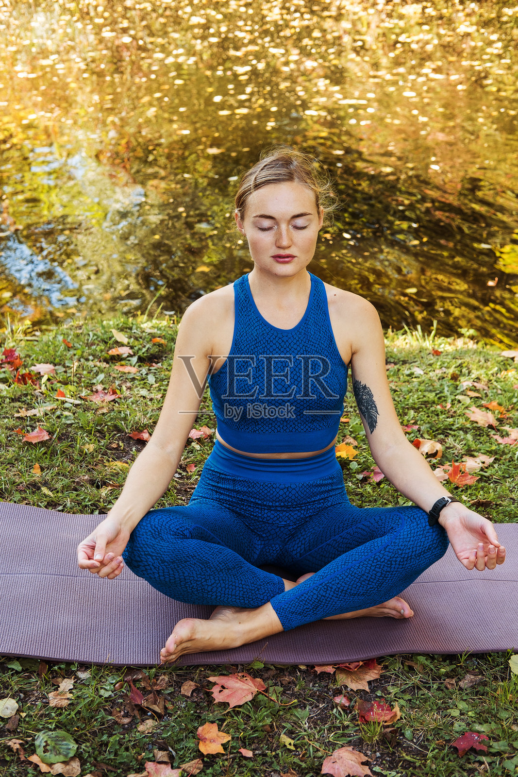 年轻女性在公园户外做瑜伽练习,运动瑜伽概念。女性坐在瑜伽垫上。照片摄影图片