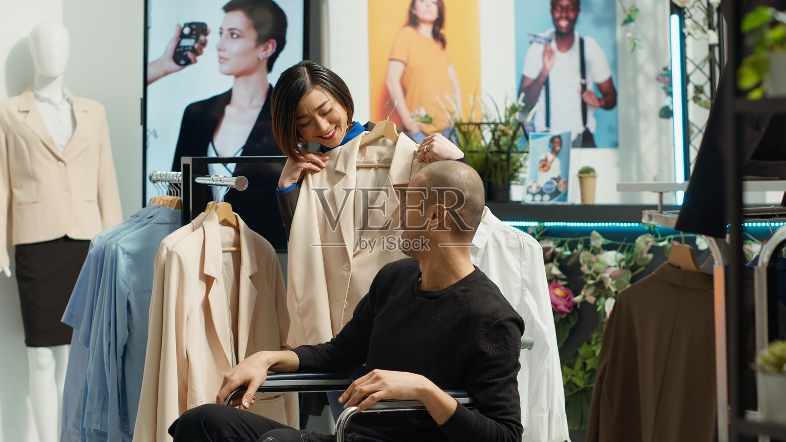 中东轮椅用户帮助他的女朋友挑选时尚衣服照片摄影图片
