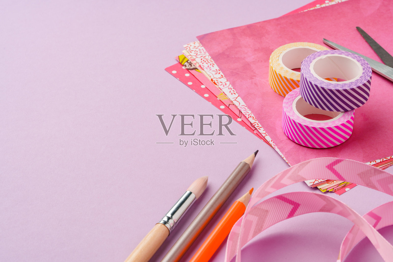 明亮工作空间中的彩色手工纸上放着剪刀和装饰胶带照片摄影图片