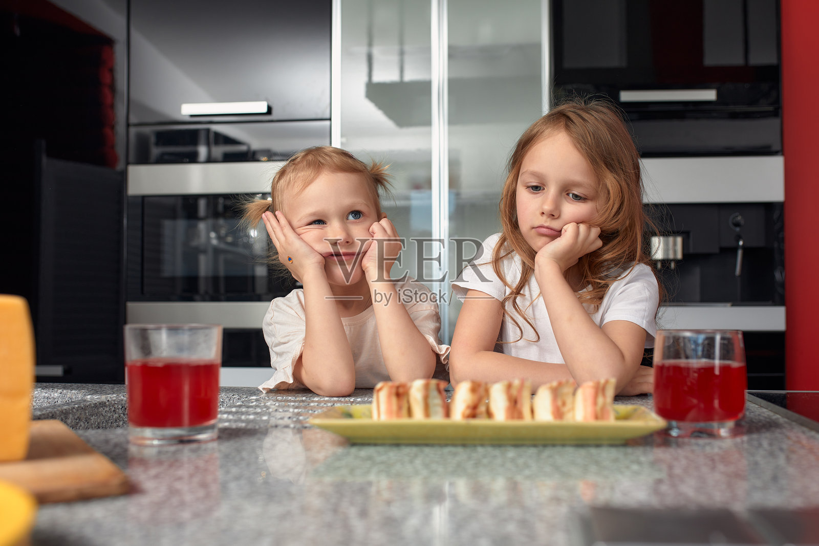 两个小女孩兄弟姐妹在家里的厨房里吃日本菜,玩得很开心。照片摄影图片
