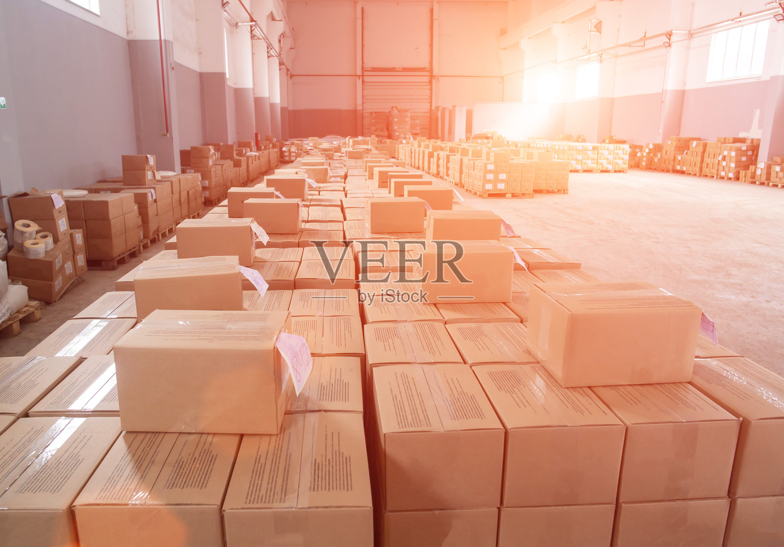 在夕阳的背景下,仓库里有许多装着包装好的产品的纸箱。概念产品包装配送于仓库、工业。文字、文具的复制空间照片摄影图片