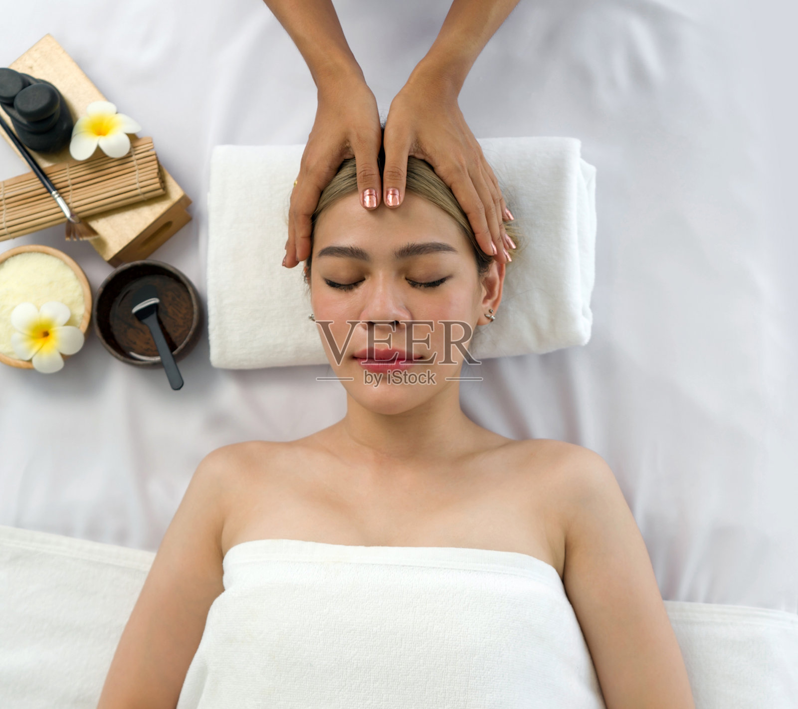 一位宁静的女性在恢复活力的水疗中心享受有益的面部按摩,帮助她恢复皮肤并提供深度放松。照片摄影图片