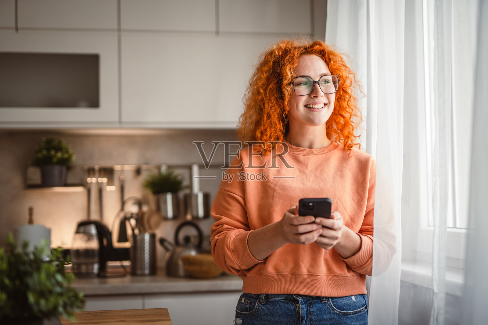 美丽女性在厨房里站着使用手机的肖像照片摄影图片
