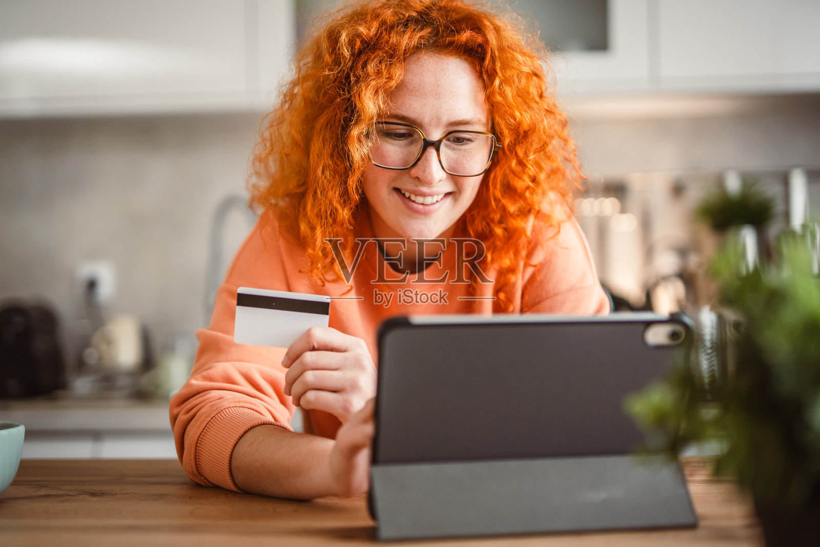 女性在吃沙拉,同时使用平板电脑和信用卡付款照片摄影图片