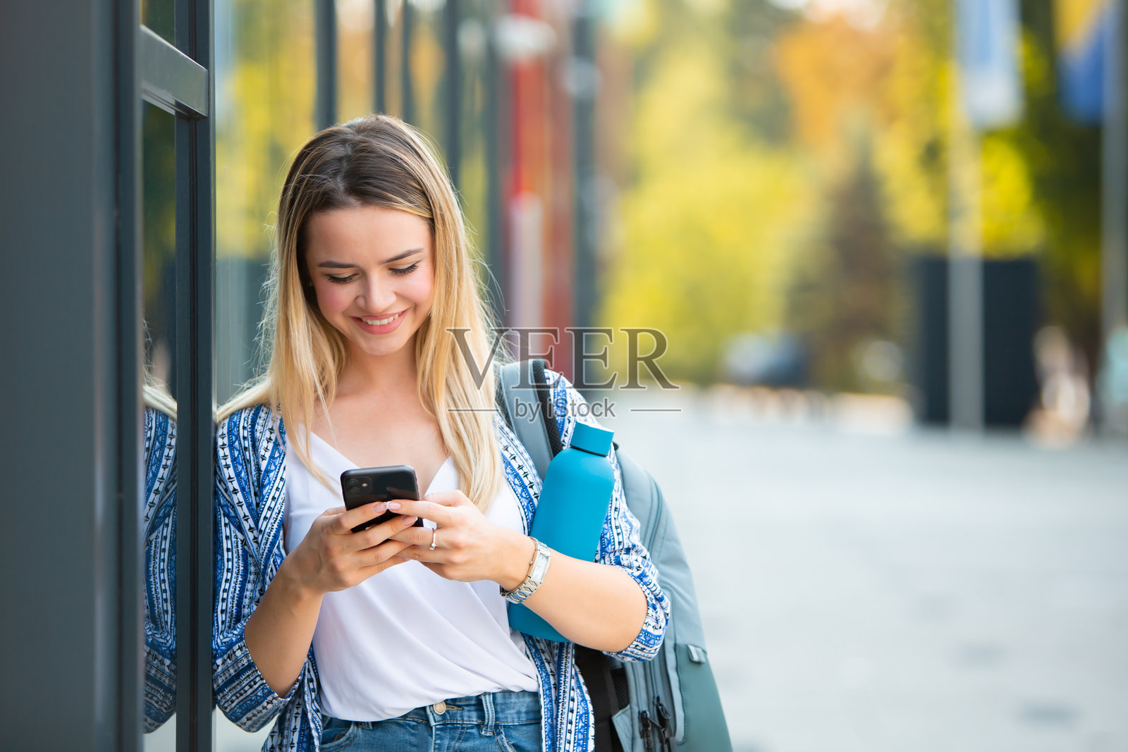 年轻金发女性在现代办公大楼外使用手机照片摄影图片