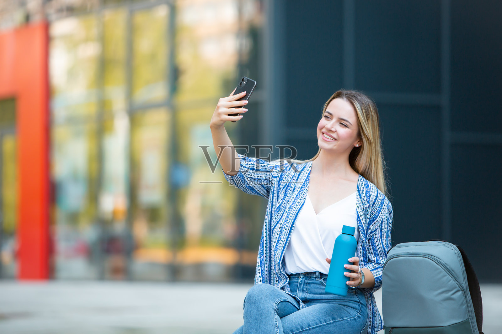 年轻金发女性在现代办公大楼外使用手机照片摄影图片