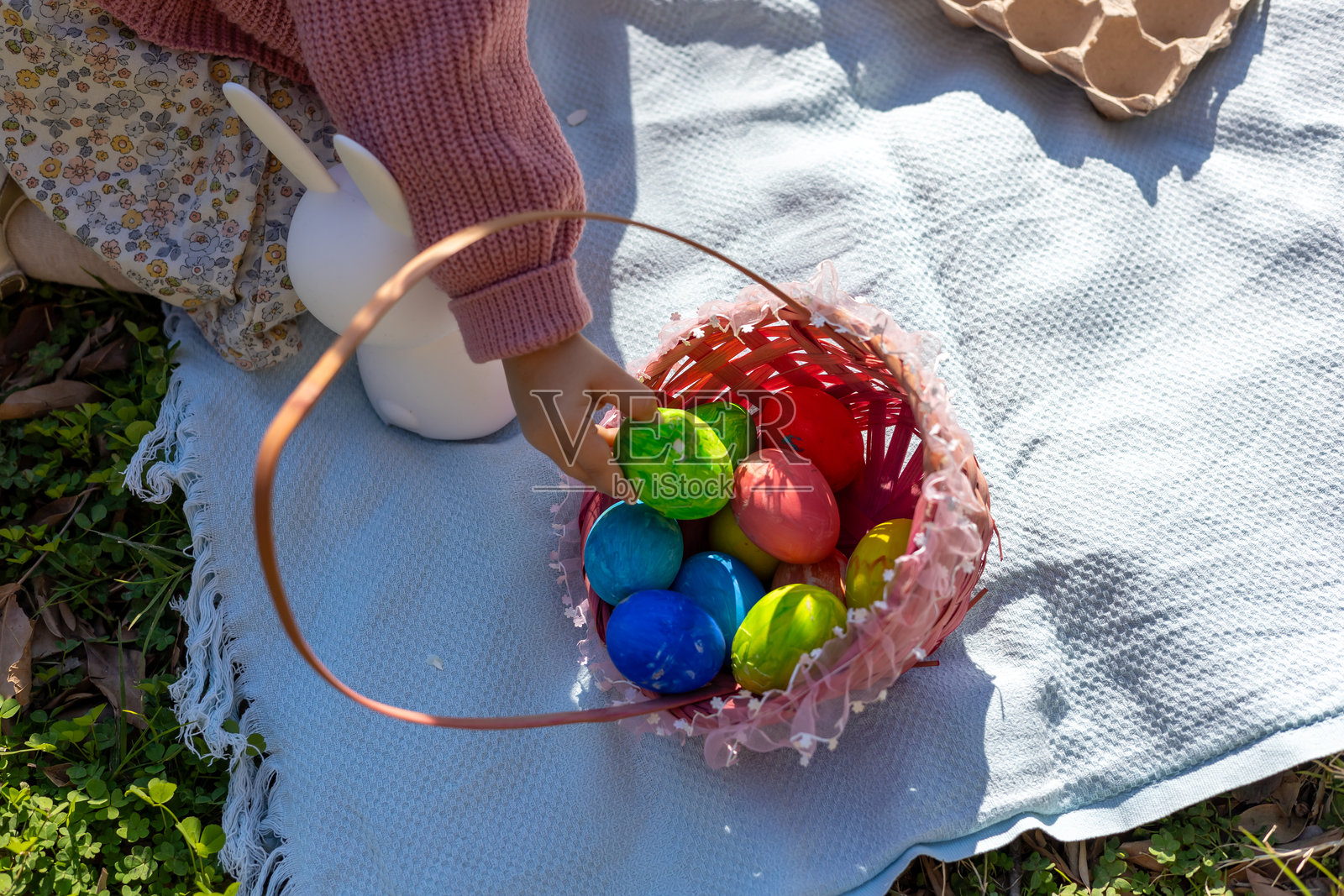 阳光明媚的花园里,孩子正在收集五彩缤纷的复活节彩蛋照片摄影图片