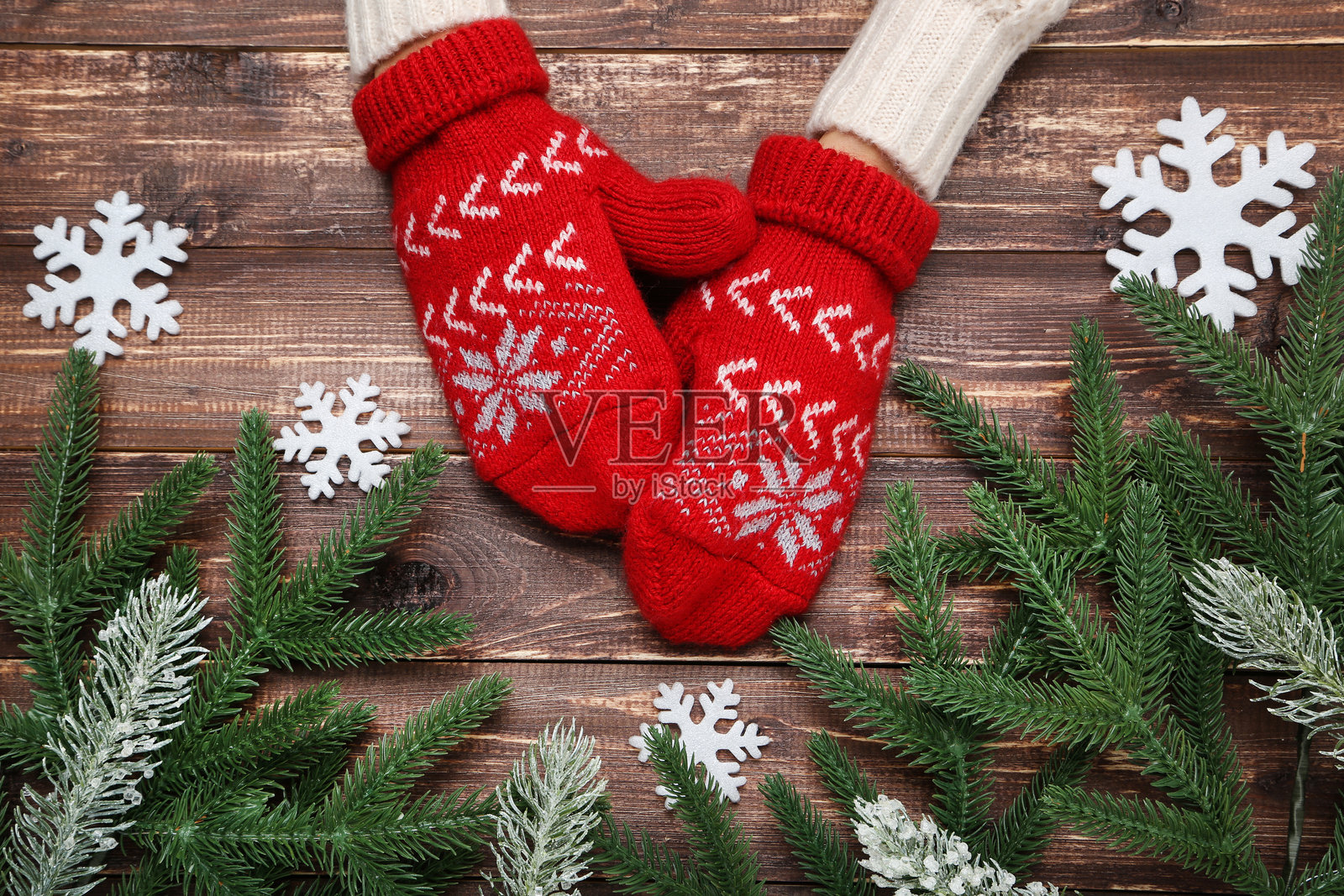 手戴着编织手套,桌上有雪花和松树枝照片摄影图片