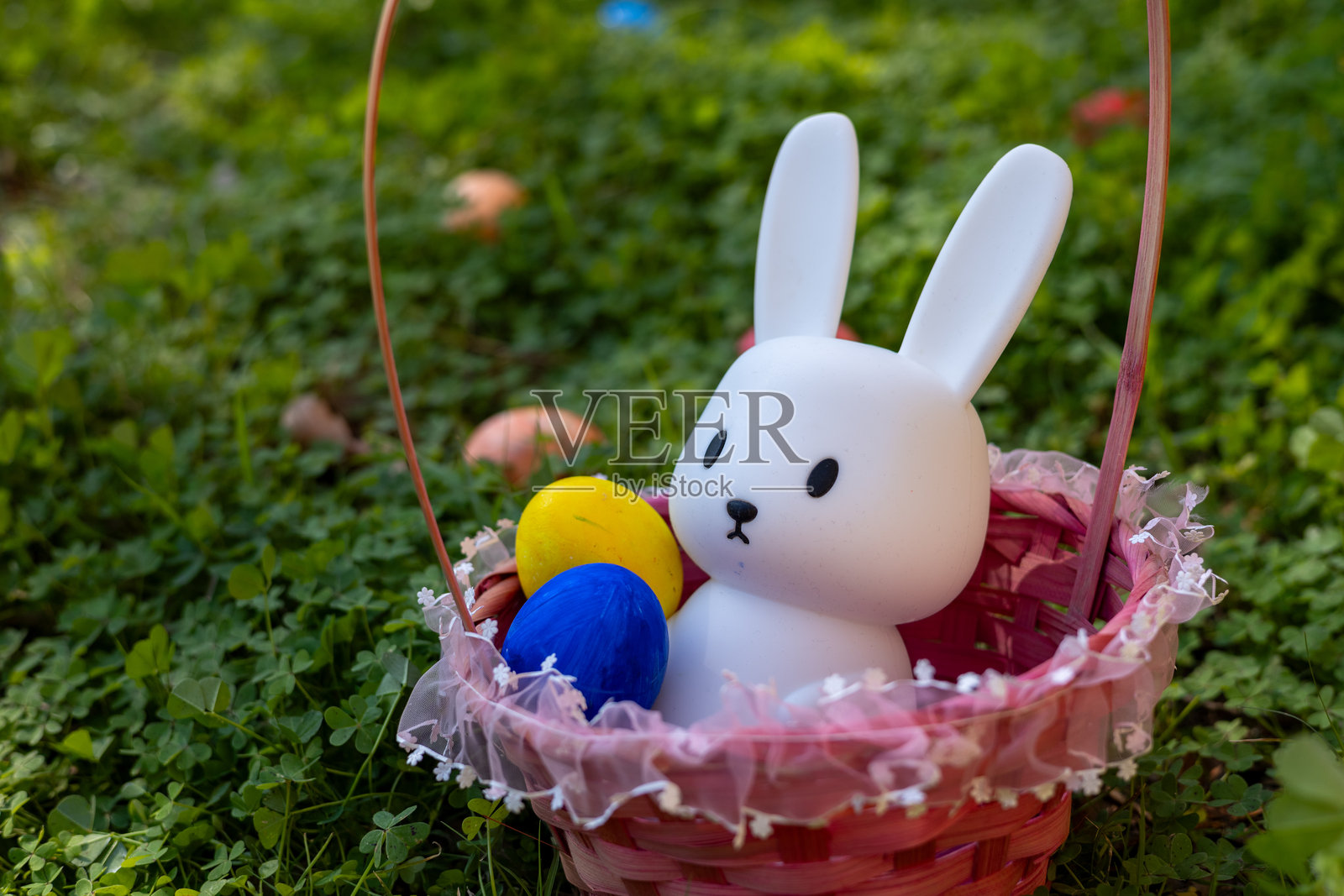 可爱的白兔子与五彩缤纷的复活节彩蛋在篮子里照片摄影图片