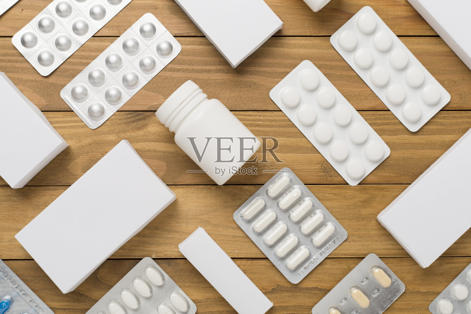平铺展示不同药丸的泡罩包装和盒子,背景为木质表面照片摄影图片