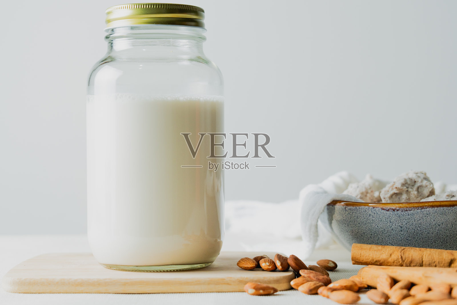 新鲜自制的杏仁奶,装在玻璃罐中,旁边有杏仁和肉桂棒照片摄影图片
