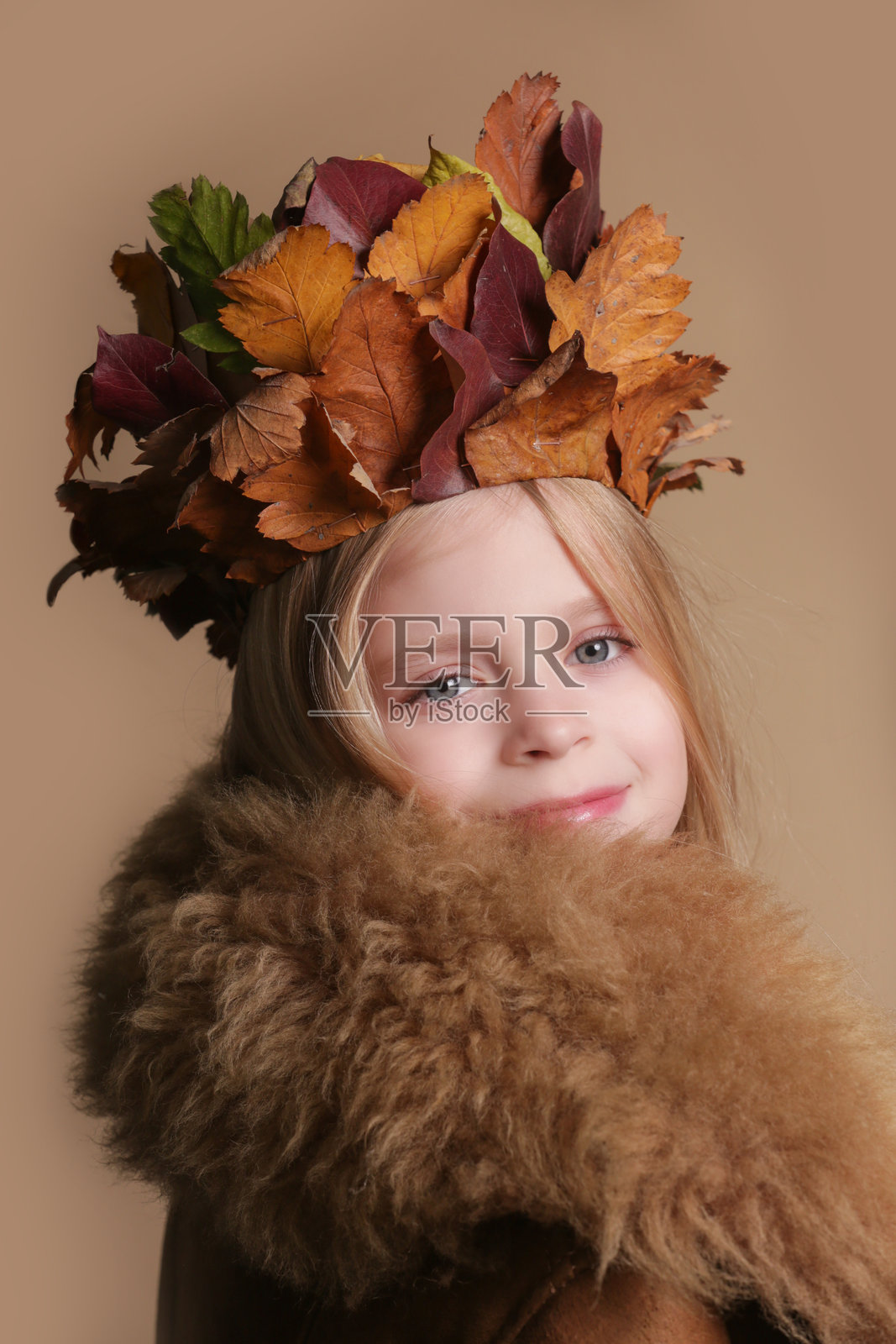 可爱的金发蓝眼小女孩戴着用干燥秋叶制作的皇冠,秋叶手工艺创意。照片摄影图片