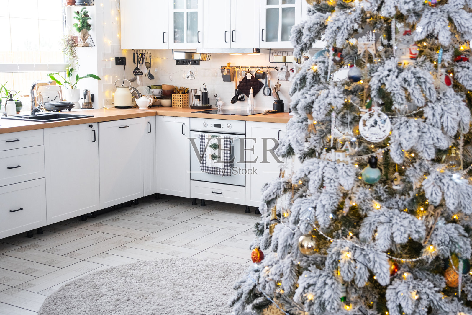 白色厨房的圣诞装饰,充满节日气氛的混乱,村庄内部有一棵雪白的圣诞树和仙女灯。新年,圣诞心情,温馨家。照片摄影图片