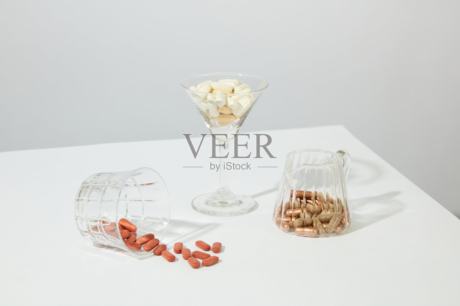 白色背景下玻璃杯中的彩色胶囊照片摄影图片