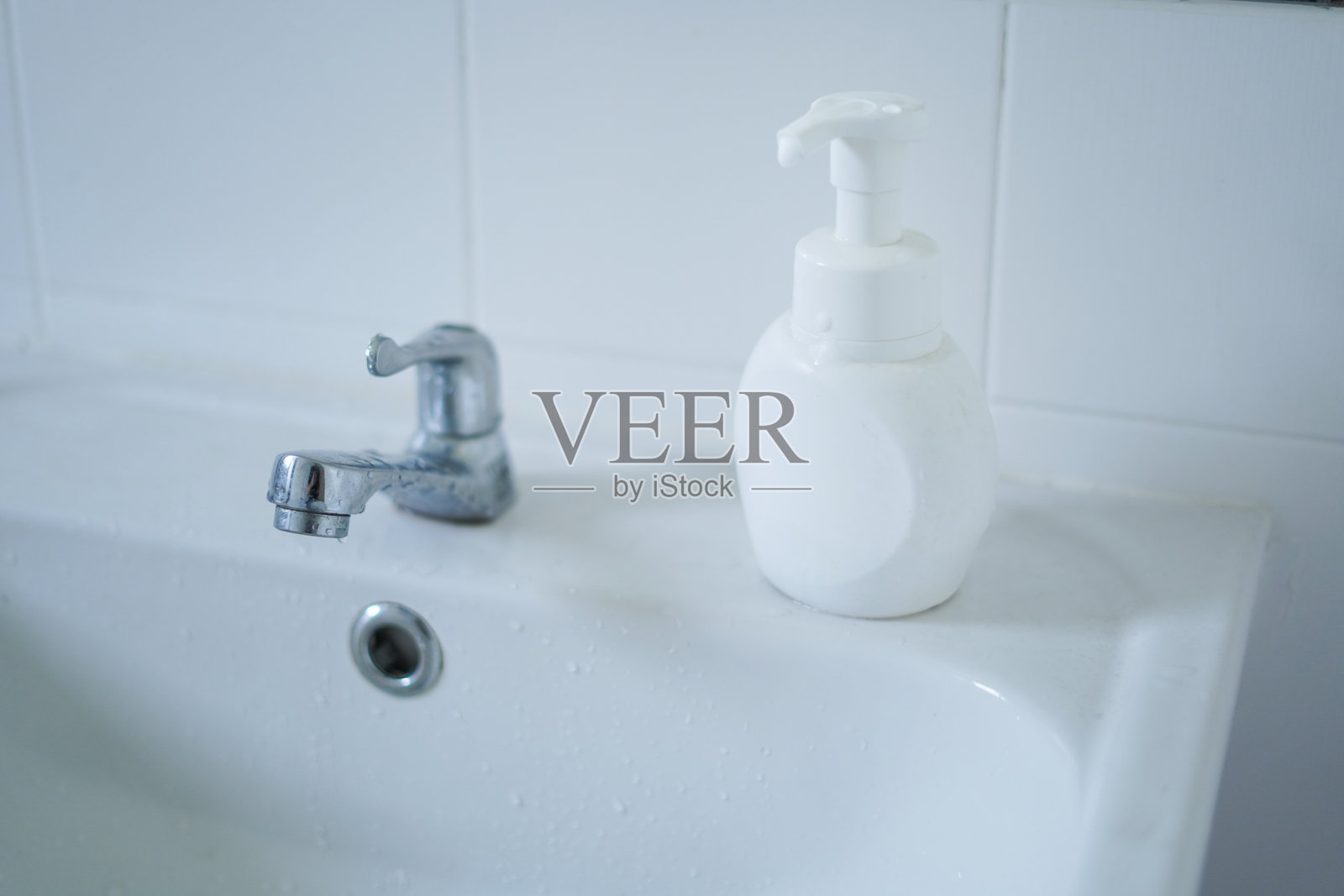 浴室里的白色洗手盆和肥皂 dispenser照片摄影图片