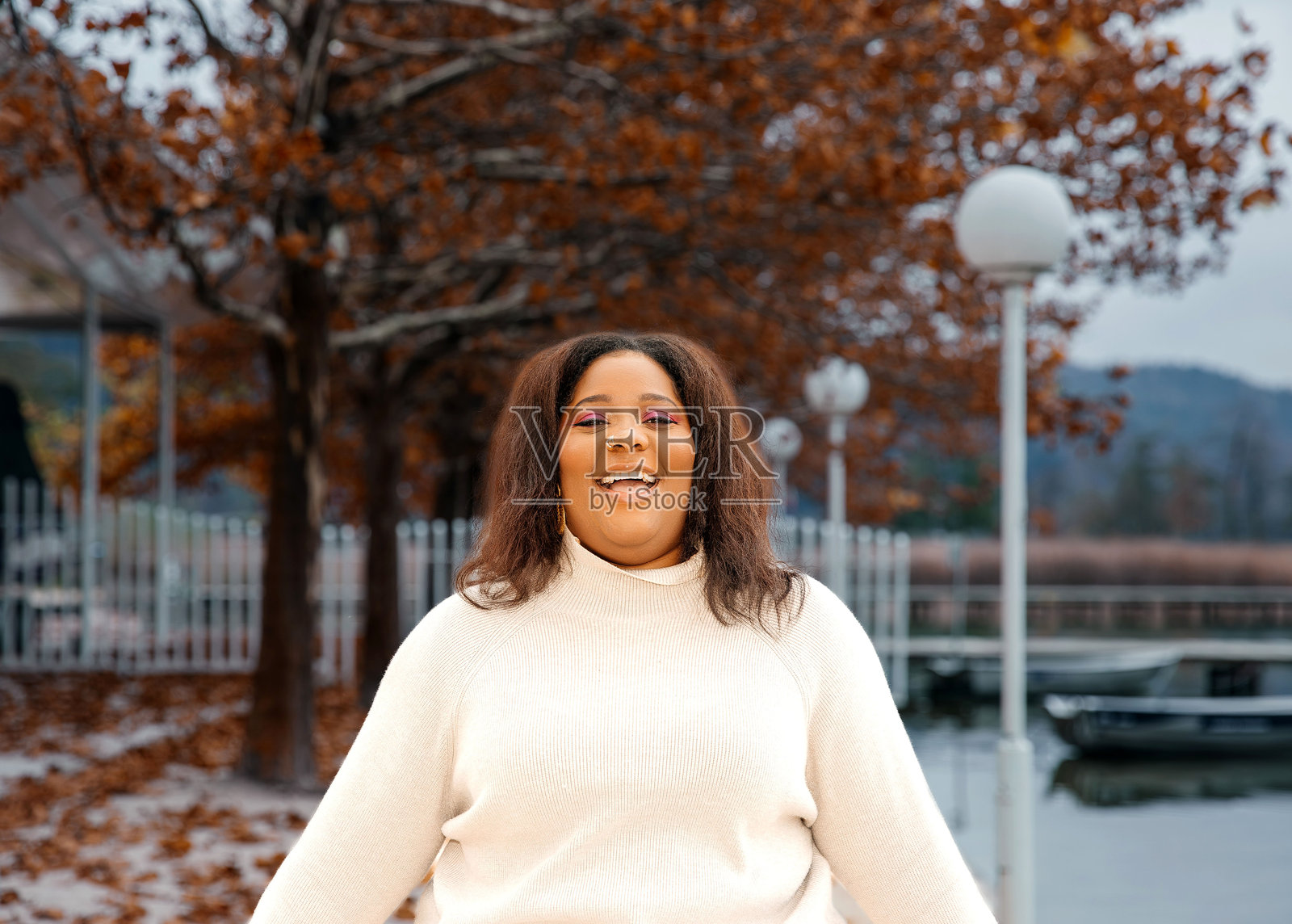 快乐的非洲女性成年人在秋天的公园里与飘落的树叶一起享受时光照片摄影图片