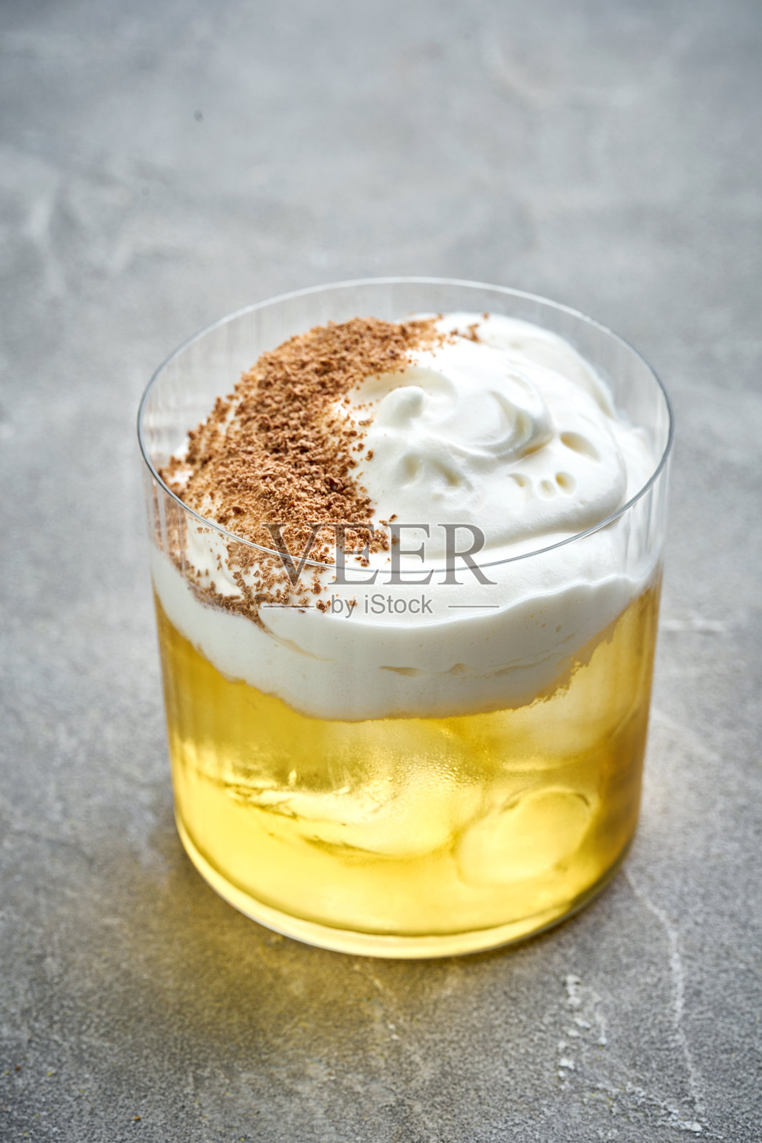 一杯清爽的威士忌酸鸡尾酒,顶部有泡沫,撒上肉桂粉作为装饰。鲜艳的色彩和优雅的呈现使这款饮品适合任何场合。照片摄影图片