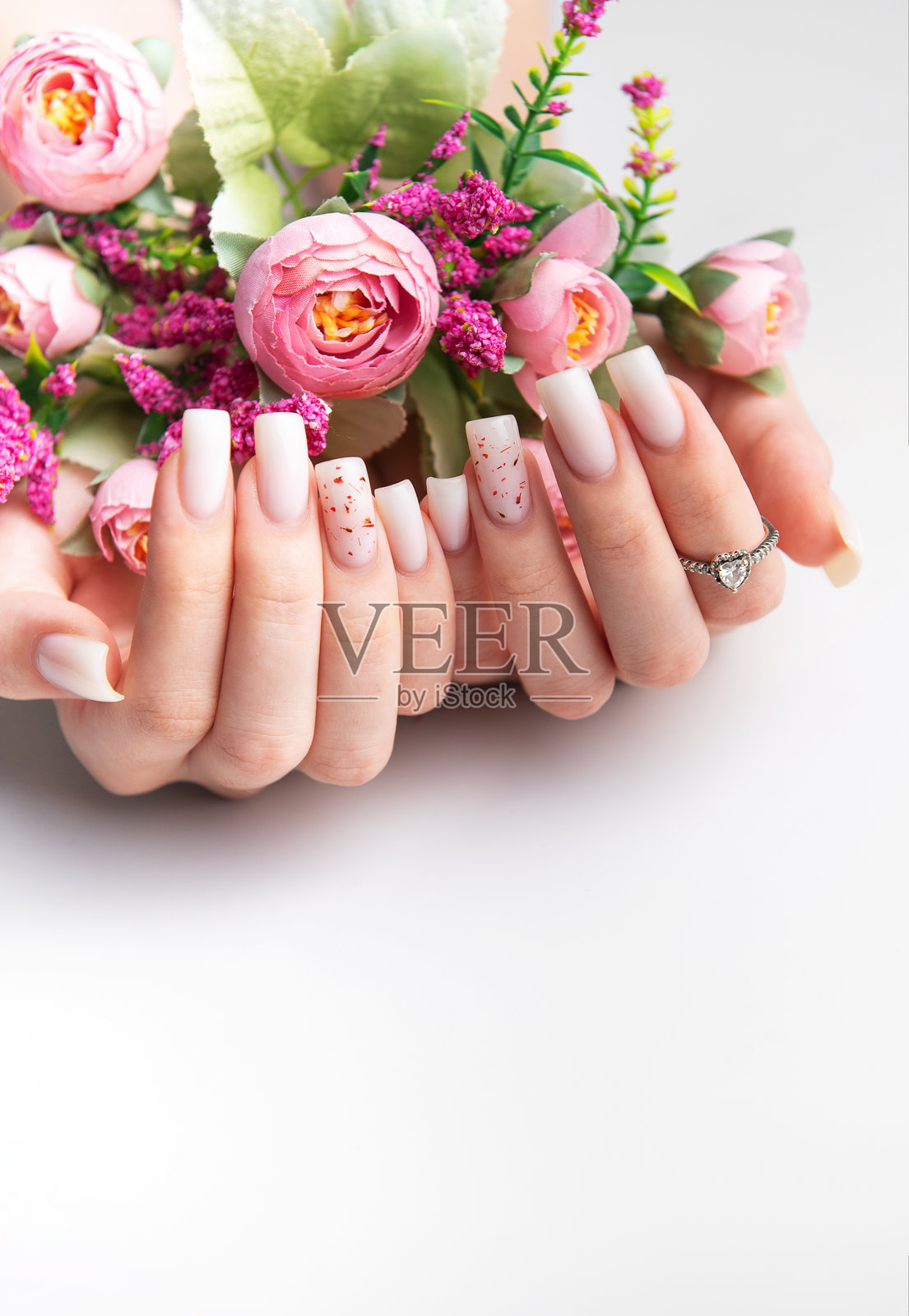 女人展示时尚的粉色美甲,手中捧着粉色花朵照片摄影图片