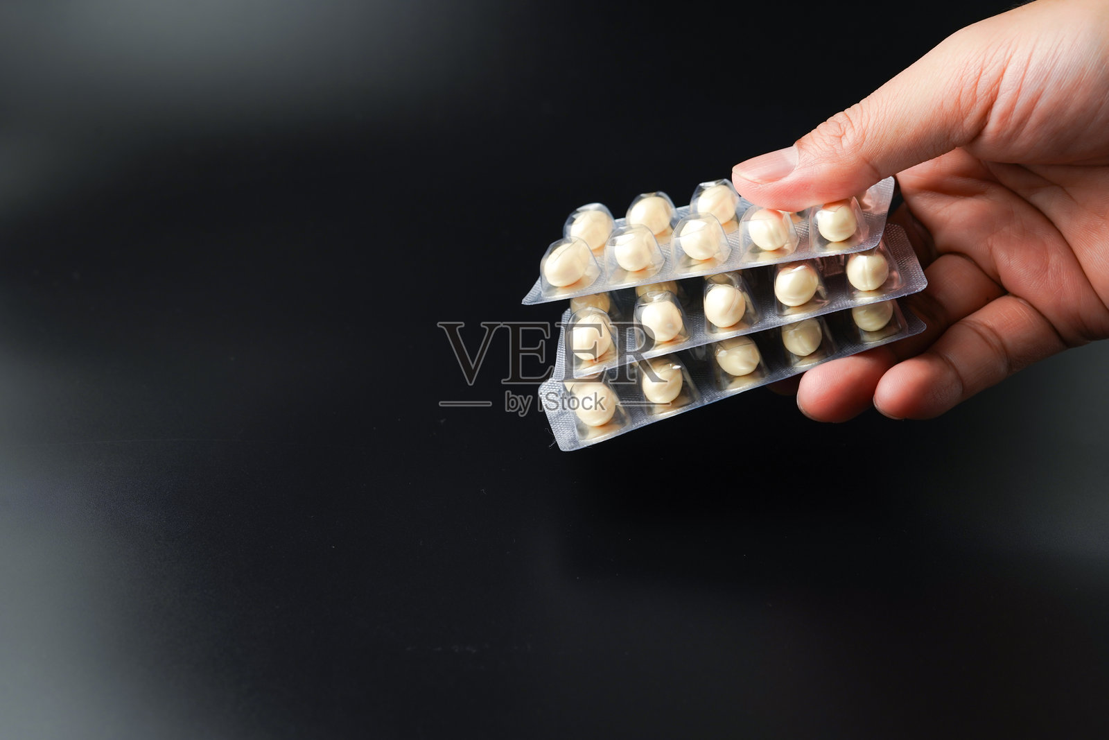 男子手持含有Omega、维生素E、鳕鱼肝油和DHA的白色软胶囊鱼油泡罩包装。照片摄影图片