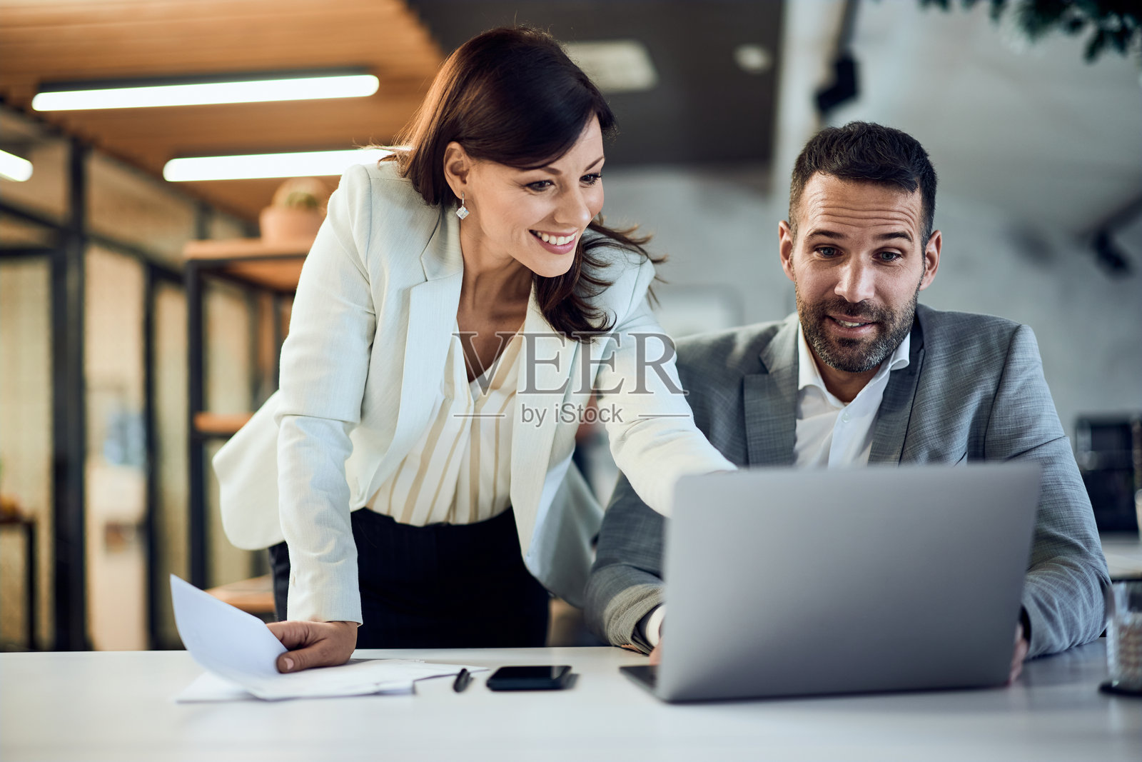 两位商业伙伴在办公室合作,使用笔记本电脑。照片摄影图片